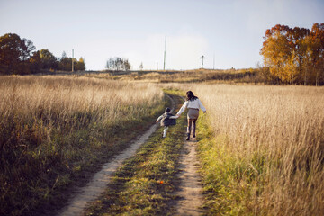 Fototapeta premium mother and her son are run in a field with dry grass at sunset