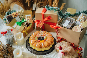 Christmas and New Year Gift Cake’s like swiss roll, pudding, tart and snack choco chips with box red ribbon accessories, brown tone warm light