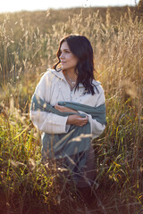 portrait of a brunette woman in a sweater and scarf in autumn in a field