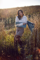 portrait of a brunette woman in a sweater and scarf in autumn in a field