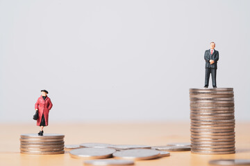 Miniature figure of businessman standing on higher than coins stacking of  businesswoman for...