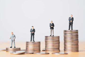 Different miniature businessman standing on different height coins stacking , Inequality income and...