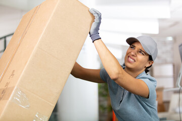 woman painfully holding a heavy boxe