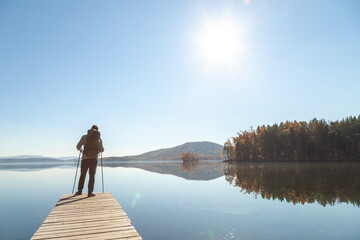 A man admires the landscape of a mountain lake while standing on the pier