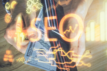 Multi exposure of seo drawing hologram and us dollars bills and man hands.
