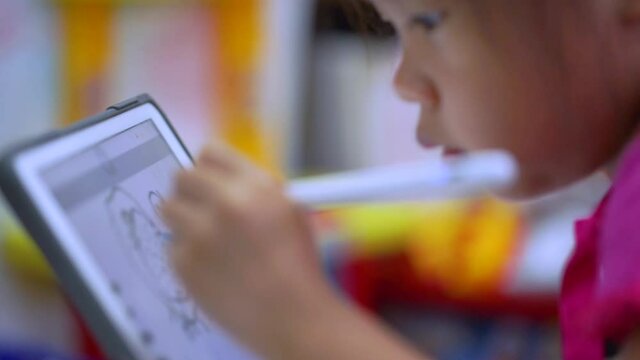Online education concept. Online class. Asian little girl studying at home. kid in living room at home and using digital tablet to draw.