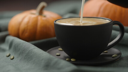 making spiced pumpkin latte in black cup, pour steamed milk