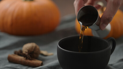 making spiced pumpkin latte in black cup, pour spiced syrup