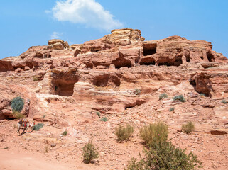 Fototapeta premium Ancient housing carved in red sand rock in the city of Petra, Jordan. Rocky landscape from Petra, Jordan.