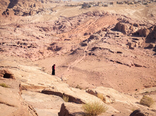 Alone bedouin woman or man in the deserted city of Petra, Jordan and Wadi Musa city , in the background