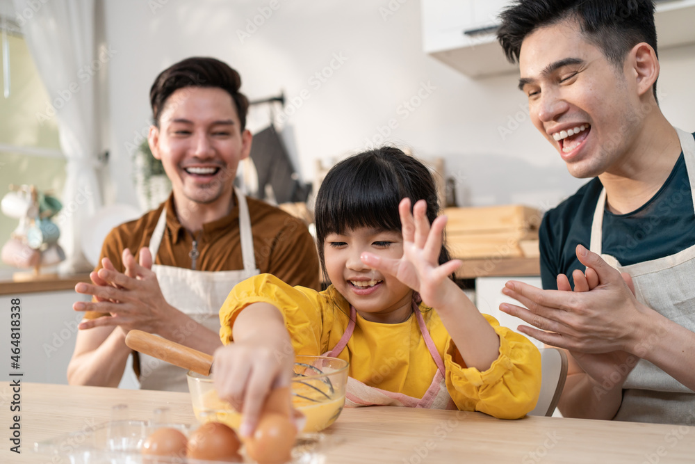 Wall mural asian lgbtq male gay family teach girl kid stirring eggs in kitchen.