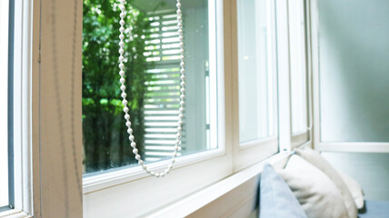 Curtain pull cord by the window with sunlight.