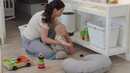 Mother and baby cleaning up toys together on the floor after playing, mom teaches her child to tidying up toys at home. High quality 4k footage