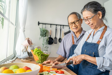 Asian loving senior elderly couple wear apron and cooking in kitchen. 