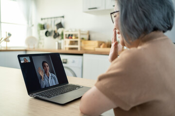 Asian senior older woman video call with doctor in living room at home. 
