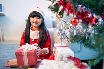 Asian young happy girl kid wear Santa hat and decorate Christmas tree. 
