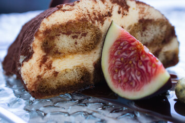 Tiramisu dessert with slice of fig. Cocoa cake with chocolate. Sweet breakfast in restaurant. Tiramisu portion with cocoa powder and fruit. Italian cuisine. Decorated mascarpone biscuit. 