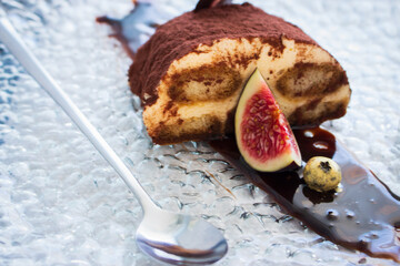 Tiramisu dessert with slice of fig. Cocoa cake with chocolate. Sweet breakfast in restaurant. Tiramisu portion with cocoa powder and fruit. Italian cuisine. Decorated mascarpone biscuit. 