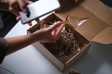 woman opens a delivery box from a store and discovers a broken glass. An improperly packed item crashed on delivery