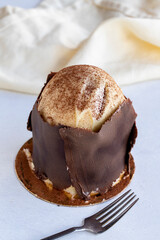 Cake with banana and profiteroles on a white background. Small celebration dessert covered with chocolate on the outside