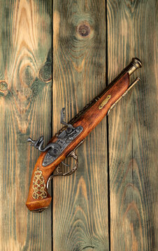 Top view of an old pistol on a wooden background.
