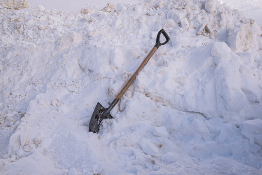 a shovel with a wooden handle lies in a large snowdrift