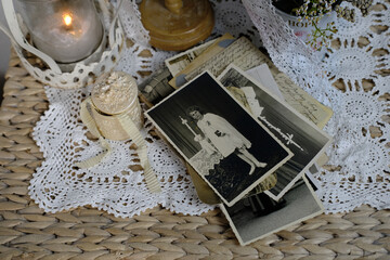 burning candle, lace, old chest of drawers shabby chic, stack of retro photos of 50-60s, dried flowers, concept of family tree, genealogy, connection with ancestors, memories of youth