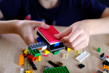 child, kid plays with colored plastic parts of the constructor, creates buildings, equipment,...