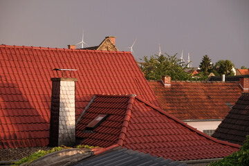 Red tiled roofs of a German village on the wind power station background. Evening golden hour after rain.