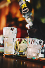hands of a bartender with black gloves making cocktail on a bar counter.
