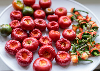 tomato peppers on a white plate, peppers prepared for canning, green stalks separated, concept of healthy eating, vegetarian diet, canning products for winter, autumn harvest time