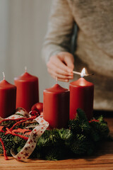Child hand lighting the first candle of Advent Wreath on the first Advent Sunday counting four weeks before Christmas. Old swiss tradition in December to celebrate Advent time.