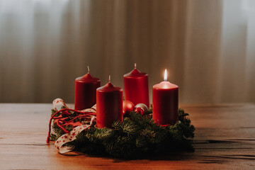 The first candle on the Advent Wreath is burning. Swiss tradition to celebrate four weeks till Christmas Eve. Cozy winter evening mood. - obrazy, fototapety, plakaty