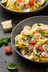 White shell clams in Garlic and parsley white wine sauce tagliatelle pasta served with cherry tomatoes and parmesan cheese
