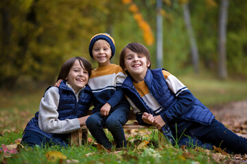 Fototapeta premium Happy family, funny children, having their autumn pictures taken in the park, playing