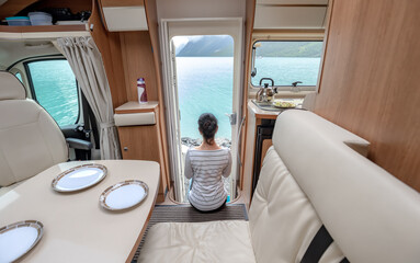 Woman in the interior of a camper RV motorhome with a cup of coffee looking at nature.