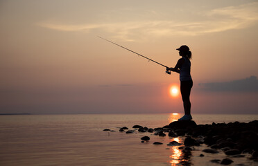 Woman fishing on Fishing rod spinning in Finland at sunset. - 464829537