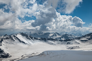 Fototapeta na wymiar Mountain clouds over beautiful snow-capped peaks of mountains and glaciers. View at the snowy mountains.