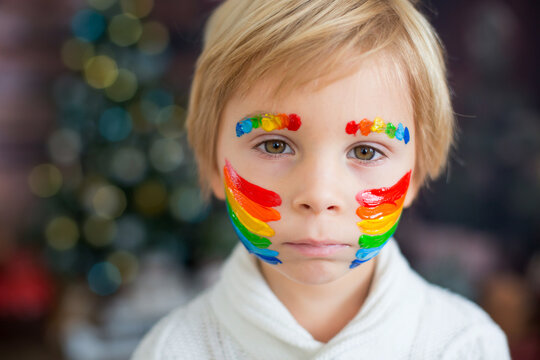 Beautiful child, toddler boy with painted face with rainbow, posing for close portrait