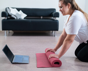 Young chubby woman preparing for an online fitness class. Distance training during the quarantine period