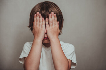 Boy crying covered his face with his hands. Stressed child. Domestic Family violence and aggression concept violence - obrazy, fototapety, plakaty