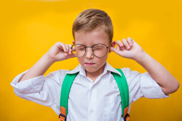 Photo of tired annoyed boy avoid noise fingers cover ears wear school uniform isolated yellow color...