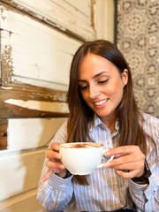 mujer hermosa y sonriente tomando un café con leche en una cafeteria 