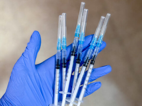 vacunas de covid19 en una mano con un guante preparadas para inyectar