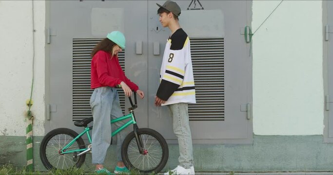 A loving couple of teenagers on a date. The guy is trying to kiss the girl. Young modern woman flirts with a man. 4k raw video footage