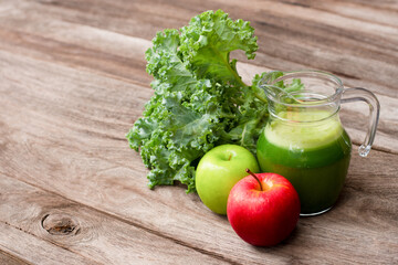 Healthy green smoothie juice in glass jug with kale vegetable and  apples on wooden table background. Antioxidant, superfood, detox healthy drinks concept.