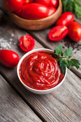 Homemade tomato sauce in white bowl, fresh tomatoes, spices and herbs. Food background