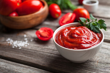 Homemade tomato sauce in white bowl, fresh tomatoes, spices and herbs. Food background