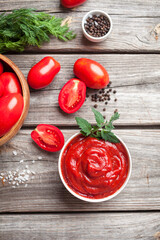 Homemade tomato sauce in white bowl, fresh tomatoes, spices and herbs. Food background