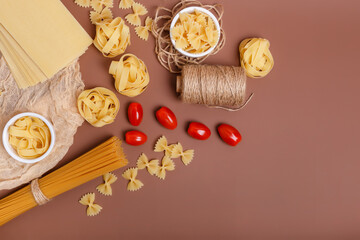 Yummy italian pasta and cherry tomatoes in rustic style on brown background. Traditional italian cuisine top view. Pasta is the traditional italian food. Spaghetti, fettuccine, farfalle flat lay view.